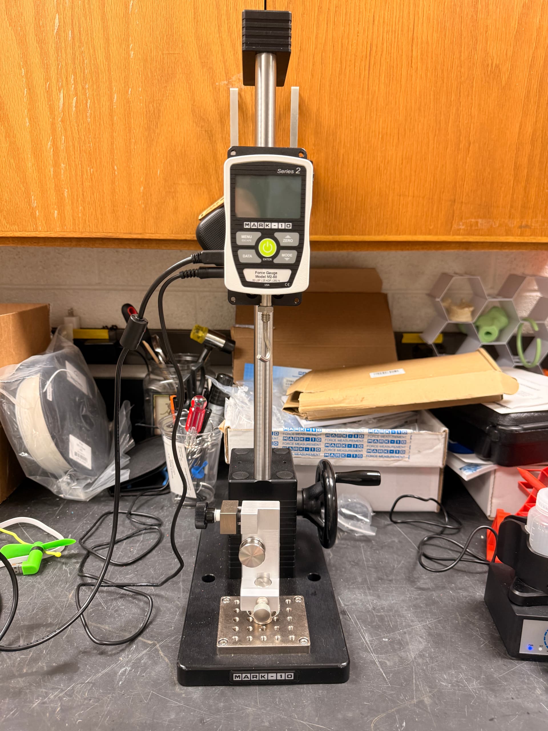 The Mark-10 M2-50 force gauge mounted on its manual test stand at the lab bench